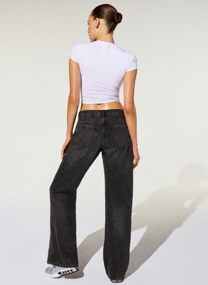 Model poses in a white t-shirt and dark wash slouchy jeans.