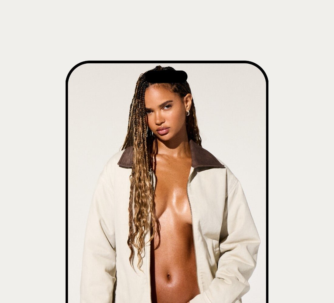 Model poses in a white worker jacket with no shirt underneath and light wash denim.