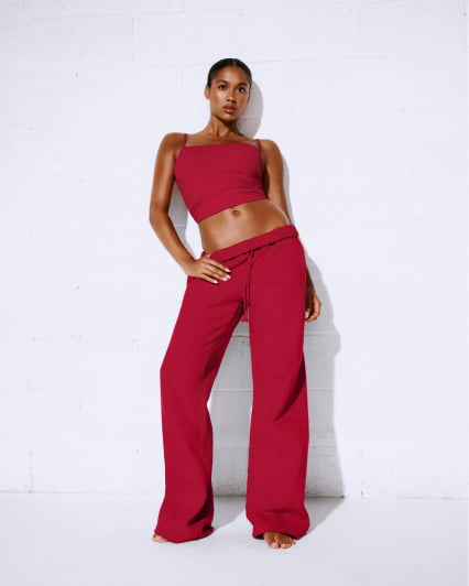Model poses in a red, long sleeve active romper.